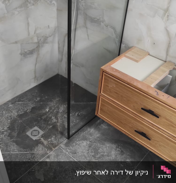 מקלחון זכוכית עם רצפה מלוכלכת וארון עץ